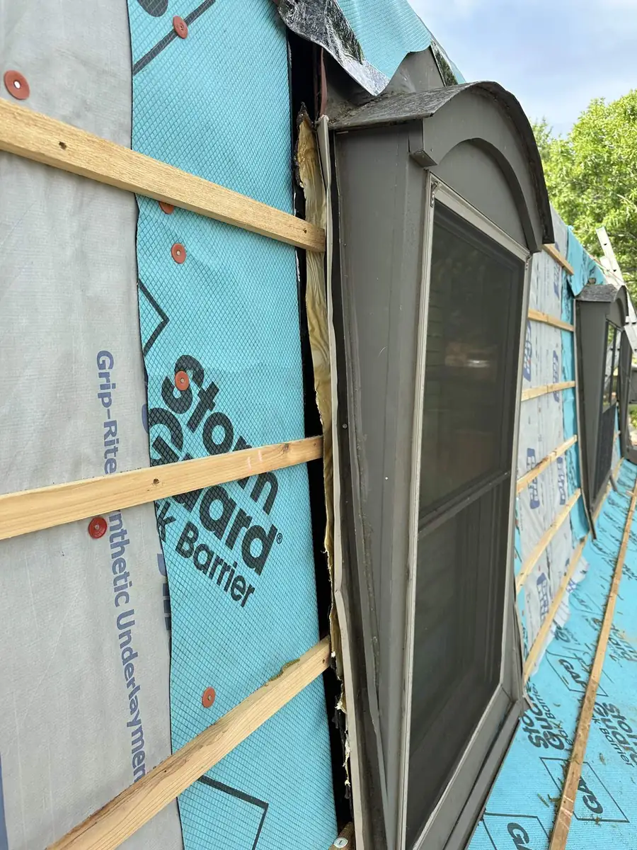 Roofers fitting custom-formed metal around a dormer