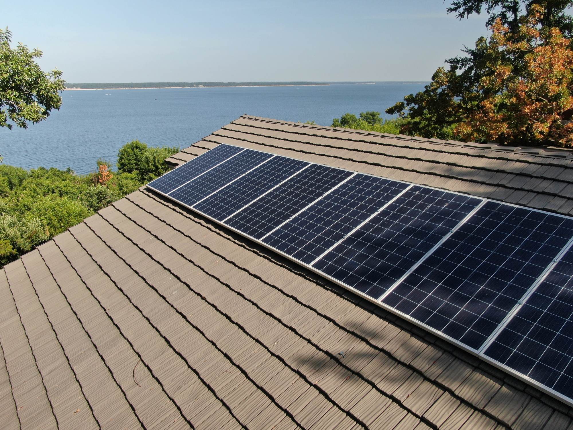 Stone-coated steel shake roof with solar panels on a lake house, installed by Big Bob's Roof Pros
